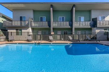 A swimming pool in front of a building with a balcony.